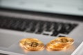 Sharp focus on golden bitcoins placed on silver laptop with blurred financial chart on its screen.