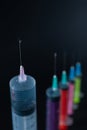 Sharp Focus on Syringe Needle Tip with Fluid Drop. A composition of various size syringes on a dark background, highlighting Royalty Free Stock Photo