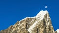Sharp Himalayan mountain peak covered in snow with the moon in the background in daytime Everest Base Camp trek Nepal