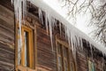 Sharp icicles hang on the edge of the roof, winter or spring. Royalty Free Stock Photo