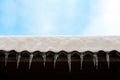 Sharp icicles hanging on the edge of the roof. Melting snow forms icicle