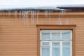 Sharp icicles hanging on the edge of the roof. Melting snow forms icicle