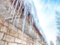 Sharp icicles from melted snow hanging from eaves of roof. Beautiful transparent icicles. Icicles on the eaves of the Royalty Free Stock Photo