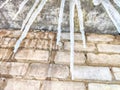 Sharp icicles from melted snow hanging from eaves of roof. Beautiful transparent icicles. Icicles on the eaves of the Royalty Free Stock Photo