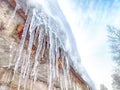 Sharp icicles from melted snow hanging from eaves of roof. Beautiful transparent icicles. Icicles on the eaves of the Royalty Free Stock Photo