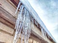 Sharp icicles from melted snow hanging from eaves of roof. Beautiful transparent icicles. Icicles on the eaves of the Royalty Free Stock Photo