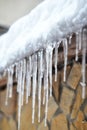 Sharp icicles and melted snow hanging from eaves of roof. Beautiful transparent icicles Royalty Free Stock Photo