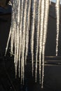Sharp icicles and melted snow hanging from eaves of roof. Beautiful transparent icicles slowly gliding of a roof Royalty Free Stock Photo
