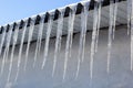 Sharp icicles and melted snow hanging from eaves of roof. Beautiful transparent icicles slowly gliding of a roof Royalty Free Stock Photo