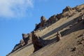 Sharp, jagged volcanic rock formations rise against a vibrant blue sky, casting long shadows on the slopes of a mountain, creating Royalty Free Stock Photo