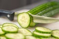 A sharp kitchen knife cuts through a cucumber on a board. Royalty Free Stock Photo