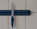 A sharp knife is attached to a magnet attached to the kitchen wall