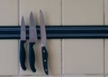 A sharp knife is attached to a magnet attached to the kitchen wall