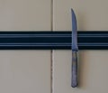 A sharp knife is attached to a magnet attached to the kitchen wall Royalty Free Stock Photo