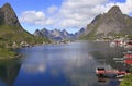 Sharp mountains, red huts and fishing boats reflected into the fjord in Reine