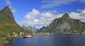Sharp mountains, red huts and fishing boats reflected into the fjord in Reine