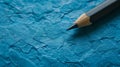 Sharp pencil tip on textured blue surface Royalty Free Stock Photo