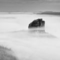 Sharp sandstone rock empire sticking out from heavy fog. Deep misty valley Royalty Free Stock Photo