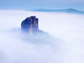 Sharp sandstone rock empire sticking out from heavy fog. Deep misty valley Royalty Free Stock Photo