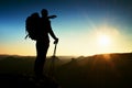 Sharp silhouette of a tall man on the top of the mountain with sun in the frame. Tourist guide in mountains