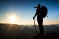 Sharp silhouette of a tall man on the top of the mountain with sun in the frame. Tourist guide in mountains