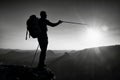 Sharp silhouette of a tall man on the top of the mountain with sun in the frame. Tourist guide in mountains
