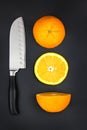 Sharp stainless steel knife and fresh orange on dark background