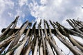 Sharp stakes of palisade stand upright against cloudy sky, view from below. Old village fence made by the hands of a farmer