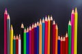 Sharpened colored pencils in diverse colors, standing tall in a wave pattern on a gray surface. Suitable for artistic, educational Royalty Free Stock Photo
