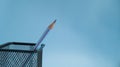 A sharpened simple pencil stands in a mesh jar on a blue background. Sharpened pencil tip. Royalty Free Stock Photo