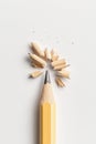 A sharpened yellow pencil with wood shavings scattered around its tip on a plain white background. Royalty Free Stock Photo