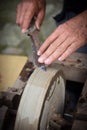 Sharpening knife on old grindstone wheel Royalty Free Stock Photo