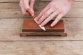 Sharpening the knife with a whetstone on a wooden background. Top view