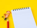Sharpening a red pencil sharpener and the note book On yellow background. Royalty Free Stock Photo