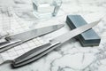 Sharpening stone and knives on white marble table Royalty Free Stock Photo