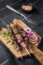 Shashlik grilled meat skewers, shish kebab with beef and lamb meat, onion and herbs. Black background. Top view Royalty Free Stock Photo