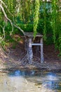 Shattered wooden pontoon bridge between willow trees near a almost dried pond Royalty Free Stock Photo