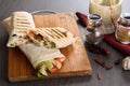 Shaurma chicken roll in a pita with fresh vegetables and cream sauce composition on wooden background Royalty Free Stock Photo