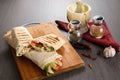 Shaurma chicken roll in a pita with fresh vegetables and cream sauce composition on wooden background