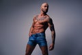 Shaved head, muscular male with tattoos on his torso over grey v Royalty Free Stock Photo