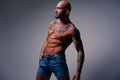 Shaved head, muscular male with tattoos on his torso over grey v Royalty Free Stock Photo