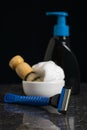 Shaving brush, foam, gel and a man`s razor on a stone table on a black background. Royalty Free Stock Photo