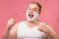 Happy plump man with shaving foam on his face and razor isolated on pink Royalty Free Stock Photo