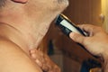 A man shaves his beard with an electric razor in front of a mirror. Care for a man`s beard at home Royalty Free Stock Photo