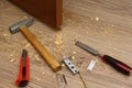 Shavings on floor from door latch installing. Wood sawdust from hole for door lock making. Hammer, chisel, knife, screws, pencil