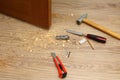 Shavings on floor from door latch installing. Wood sawdust from hole for door lock making. Hammer, chisel, knife, screws, pencil