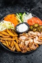 Shawarma Doner kebab on a plate with french fries and salad. Black background. Top view