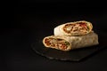 Shawarma, roll in lavash , grilled meat, with vegetables, sandwich , cut on a black background, horizontal, copy spase Royalty Free Stock Photo