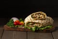 Shawarma, roll in lavash , grilled meat, with vegetables, sandwich , on a wooden brown background, horizontal, copy spase