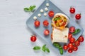 Shawarma sandwich or lavash with fresh vegetables and sauce on the gray plate decotated with cherry tomatoes, basil leaves